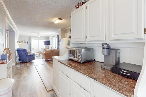 a kitchen with white cabinets and a counter top with a microwave at Captain's Villa 6-B in Holden Beach