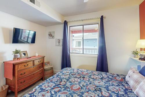 a bedroom with a bed and a dresser and a window at Captain's Villa 6-B in Holden Beach