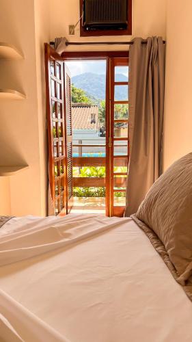 a bedroom with a bed and a window with a view at Pousada Ubatuba Villa Tupi in Ubatuba