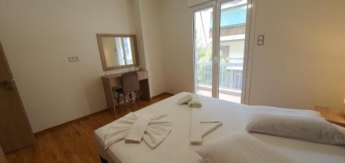a white bed in a room with a large window at A few minutes from Siggrou Street in Athens