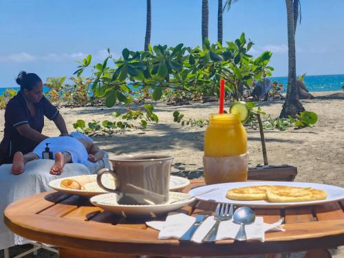 a woman sitting at a table on the beach at Beach Suite cerca al Tayrona in Santa Marta
