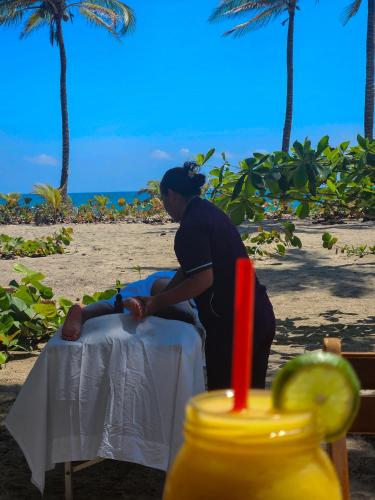 a woman sitting at a table on the beach at Beach Suite cerca al Tayrona in Santa Marta
