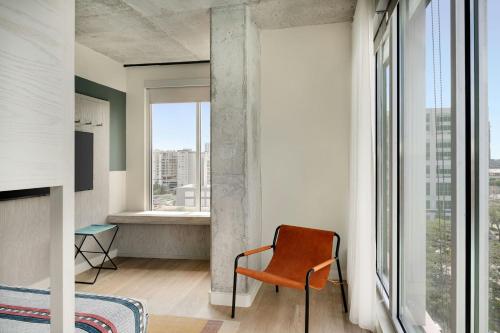 an orange chair in a room with a large window at Moxy Charlotte Downtown in Charlotte
