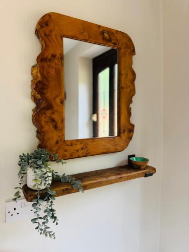 a mirror with a wooden frame on a wall at Hafan Deg in Llanferres