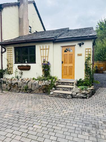 a small white house with a brown door at Hafan Deg in Llanferres