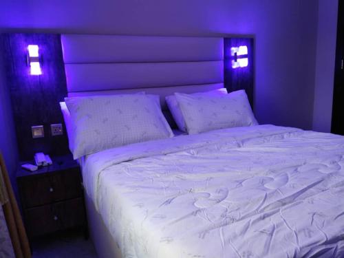 a large bed with white sheets and pillows on it at Basil Hotel and Suites in Otu