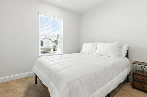 a white bed in a white room with a window at Charming Easley Retreat with Private Yard townhouse in Easley