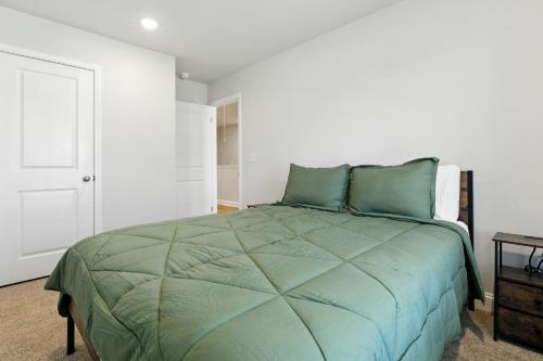 a bedroom with a bed with a green comforter at Charming Easley Retreat with Private Yard townhouse in Easley