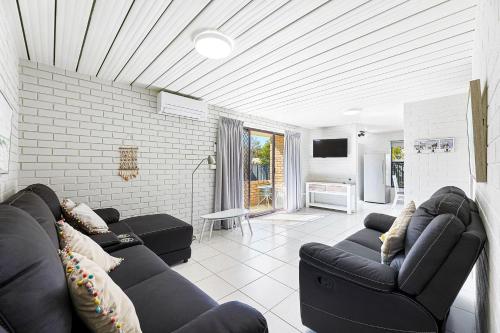 a living room with black couches and a tv at Apollo Unit 28 Ground Floor in Narooma