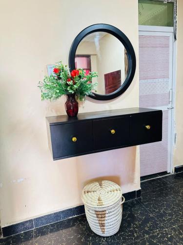 a black dresser with a mirror and a vase with flowers at Elegant & Modern 3-Bedroom Apartment Central Downtown Escape in Dar es Salaam
