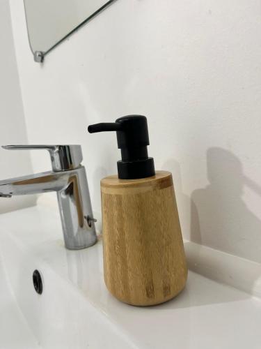a wooden soap dispenser on a sink next to a faucet at Studio Bethel cosy à Villejuif centre Paris in Villejuif