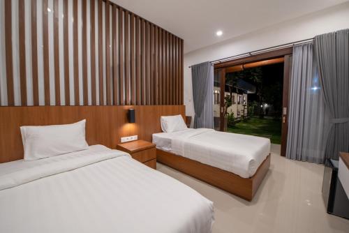 サヌールにあるBaruna Homestay Sanurのベッド2台と窓のある寝室