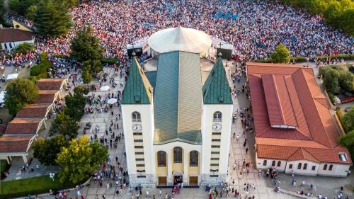 a large crowd of people standing around a church at Apartment Lumar in Ljubuški