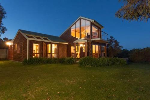 a house with the lights on in a yard at Illangi Beach Retreat in Waratah Bay