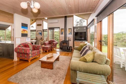 a living room with couches and a tv at Illangi Beach Retreat in Waratah Bay