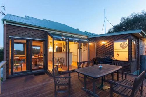 a house with a table and chairs on a deck at Illangi Beach Retreat in Waratah Bay