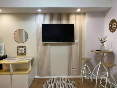 a living room with a television on a wall with stools at RL Cozy Staycation MACTAN by AMANI GRAND RESORT and RESIDENCES in Mactan Cebu International