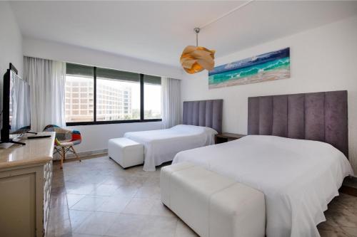 a hotel room with two beds and a tv at State of the Art Condos en la mejor Playa de Cancun frente a PLAZA LA ISLA in Cancún