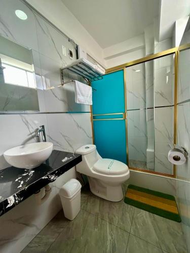 a bathroom with a white toilet and a sink at Hotel Las Palmeras in Huacho