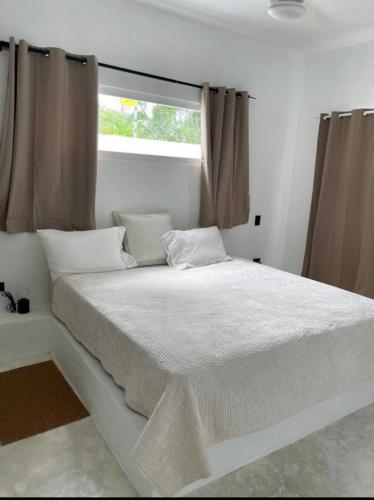Una cama blanca en una habitación con ventana. en Villa Iana BN, en Puerto Plata