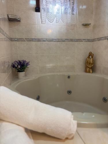 a bathroom with a bath tub with a towel at Casa Confortável 03 Quartos Com Suite, Churrasqueira, Banheira e Garagem in Curitiba