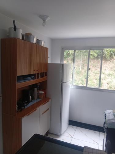Una cocina con un refrigerador blanco y una ventana. en COBERTURA DUPLEX 301CONDVILLAGE DAS ONDAS COM VISTA do MAR, en Piúma