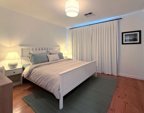una camera da letto bianca con un letto bianco e una finestra di 4BR Retreat Near McLaren Vale Wineries Adelaide a Clarendon