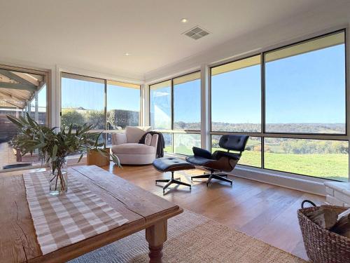 a living room with a table and chairs and windows at 4BR Retreat Near McLaren Vale Wineries Adelaide in Clarendon