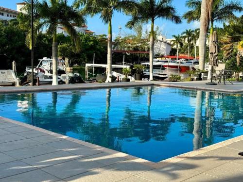 a large blue swimming pool with palm trees and boats at Luxury Holiday Apartment by the Lagoon in Cancún
