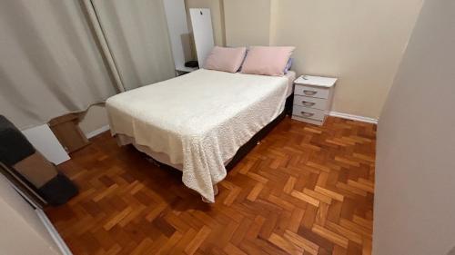 a small bedroom with a bed and a wooden floor at Apartamento Pé Na Areia, Vista Praia de Copacabana in Rio de Janeiro