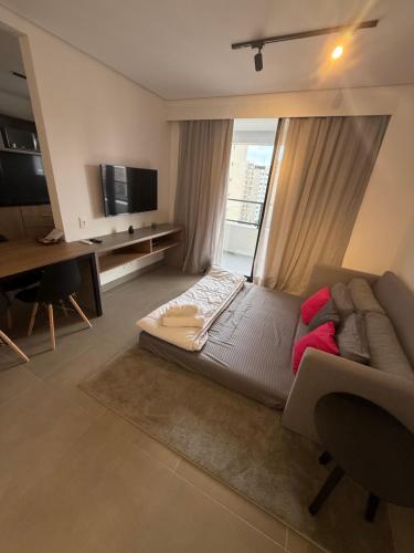 a living room with a couch and a large window at Santos Comfort - Perto da Praia in Santos