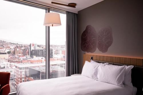 a hotel room with a bed and a large window at Crowne Plaza Hobart by IHG in Hobart