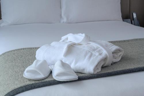 a pair of white slippers sitting on a bed at Crowne Plaza Hobart by IHG in Hobart