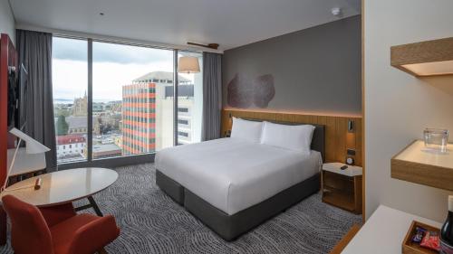 a hotel room with a bed and a desk and a window at Crowne Plaza Hobart by IHG in Hobart