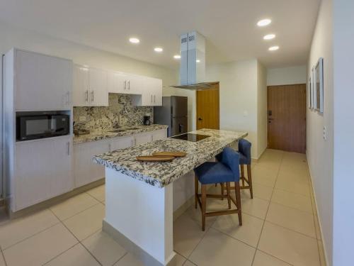 a kitchen with white cabinets and a island with bar stools at 2BR Apt with Lagoon View in Puerto Aventuras in Puerto Aventuras
