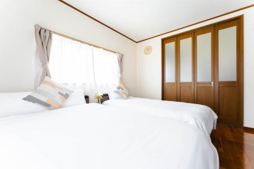 2 weiße Betten in einem Zimmer mit Fenster in der Unterkunft エアポートサイドOmura in Omura
