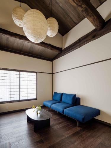a living room with a blue couch and a table at Nananohi Machiya House in Takayama