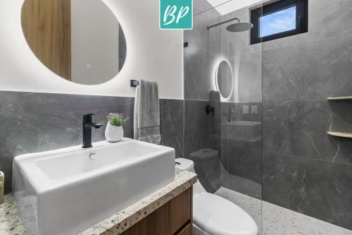 a bathroom with a sink and a toilet and a mirror at Stanza Bucerias Condos - Pool Parking & Near Beach in Bucerías