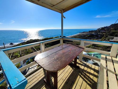 a wooden bench sitting on a deck overlooking the ocean at Cabañas Vuelo de Gaviotas in Curanipe