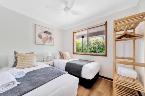 two beds in a room with a window at Bateau Bay in Bateau Bay