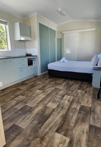 a room with a bed and a kitchen with wooden floors at NRMA Capricorn Yeppoon Holiday Park in Yeppoon