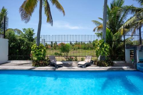 a swimming pool with two chairs and a fence at Casa Coco - 4BR | Private Pool | Hotel Zone in Cancún
