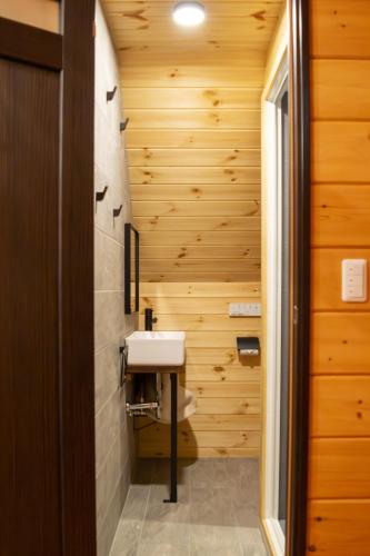 a bathroom with a sink and wooden walls at Hakuba Hills Lodge in Hakuba