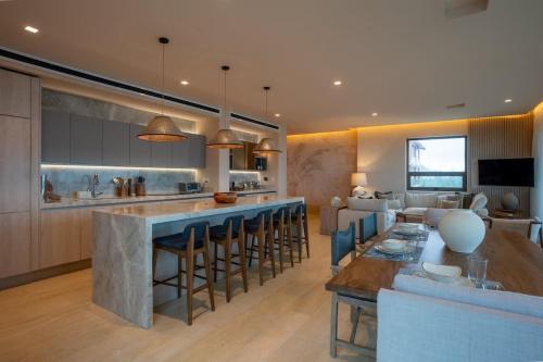 a kitchen and living room with a large bar with stools at Luxury Beachfront 4BR Apartment in Isla Mujeres in Isla Mujeres