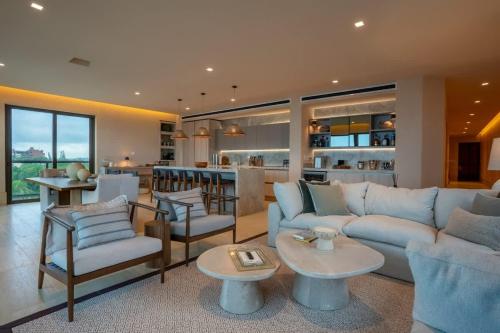 a living room with a couch and chairs and a kitchen at Luxury Beachfront 4BR Apartment in Isla Mujeres in Isla Mujeres