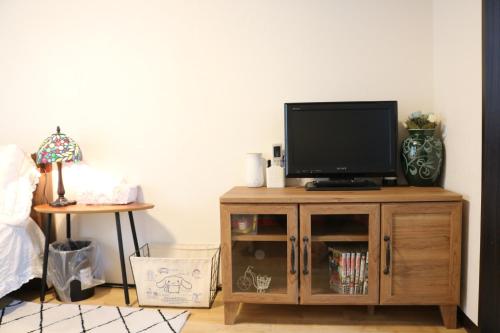 a television on a wooden cabinet in a room at Housegreen in Tokyo