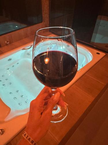a person holding a glass of wine in front of a bath tub at Chalé vista linda DM pedra azul in Domingos Martins