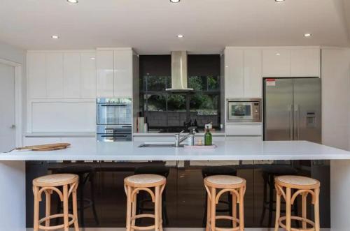 a kitchen with a large white island with stools at Hillside Hideaway Sleeps 10 Stunning Views in Howrah