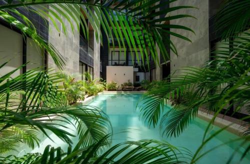 an indoor pool with palm trees in a building at 2BR Condo w/ Rooftop Oceanview & Centric Location in Playa del Carmen