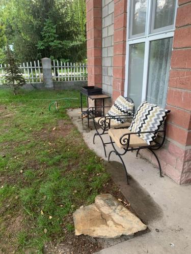 two benches sitting outside of a house with a table at Raduga West Pineforest - коттедж в аренду на Иссык-Куле in Koshkolʼ